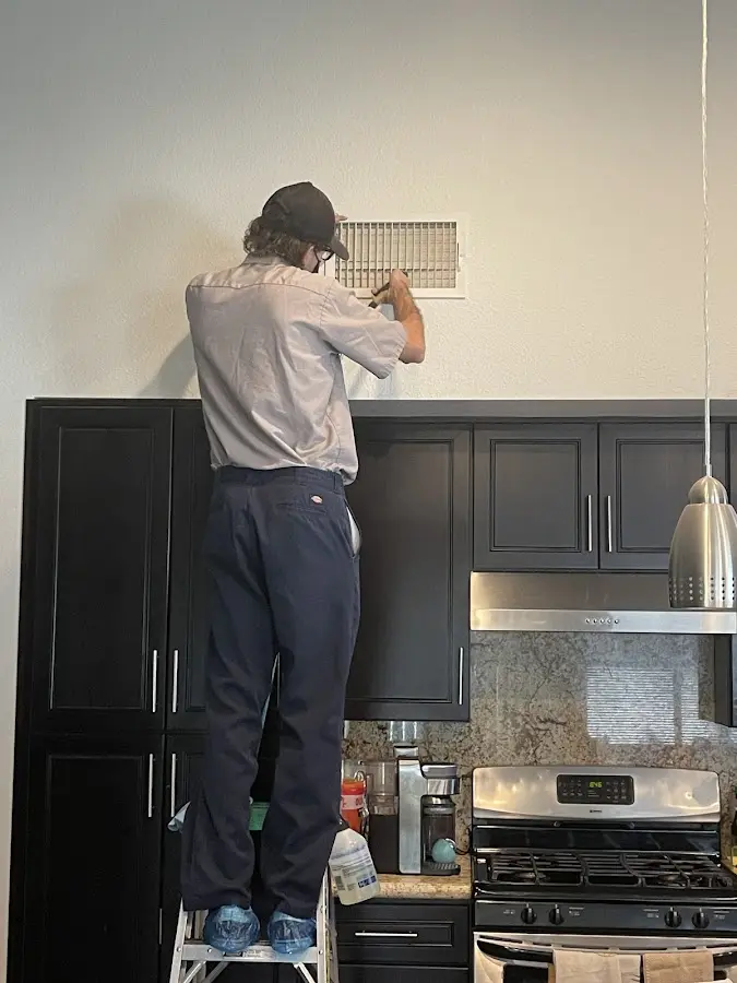 Technician inspecting an air vent during HVAC service in Port Neches